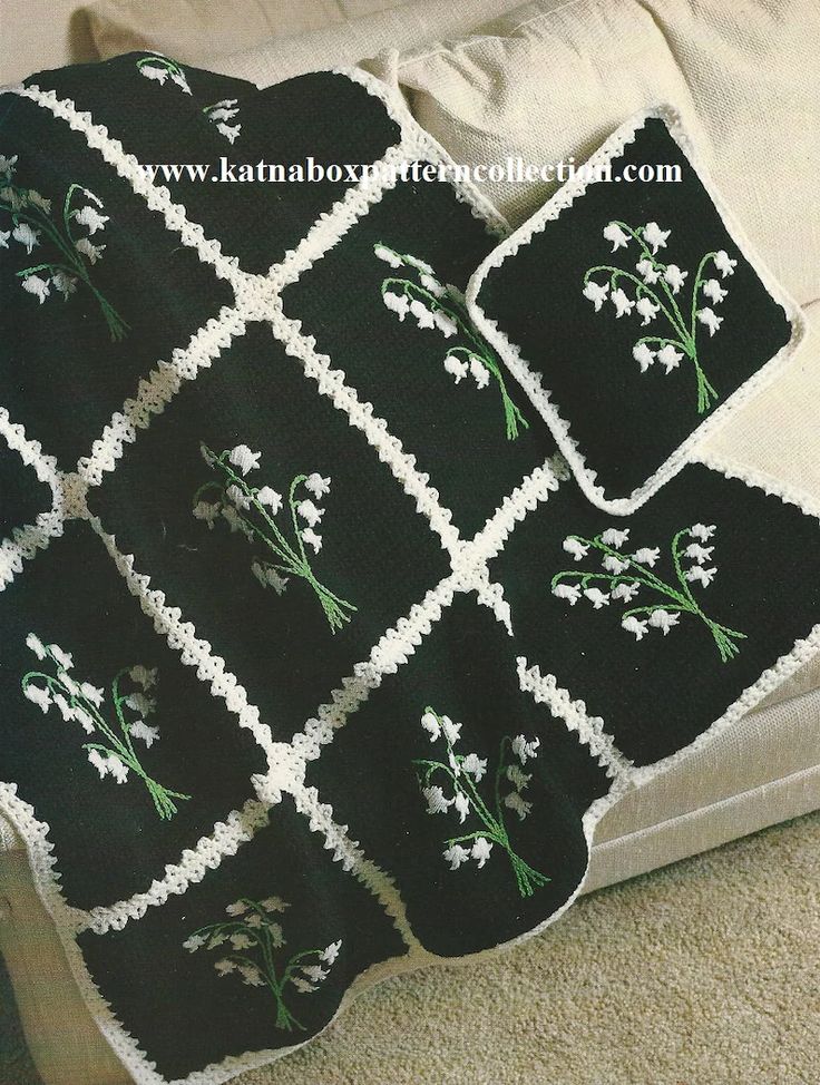 a black and white crocheted blanket on top of a couch next to pillows