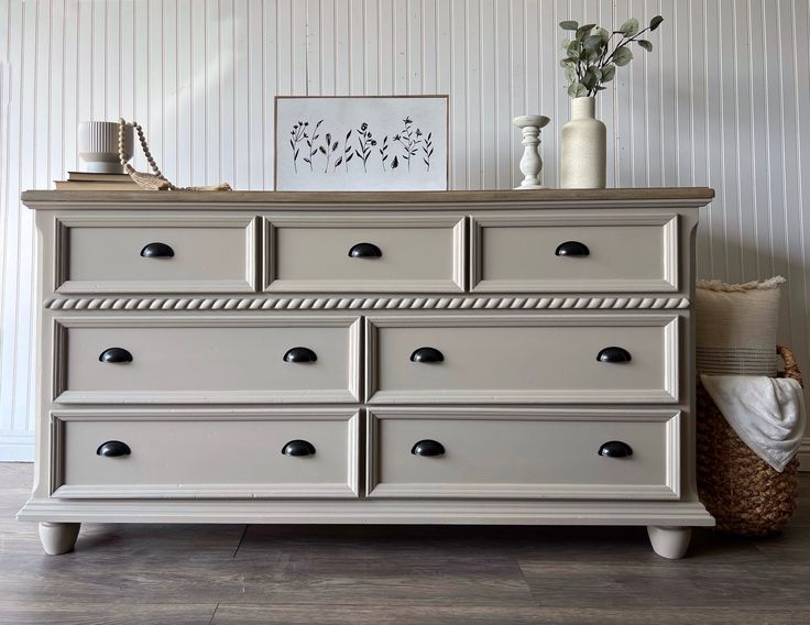 a white dresser with drawers and vases on top