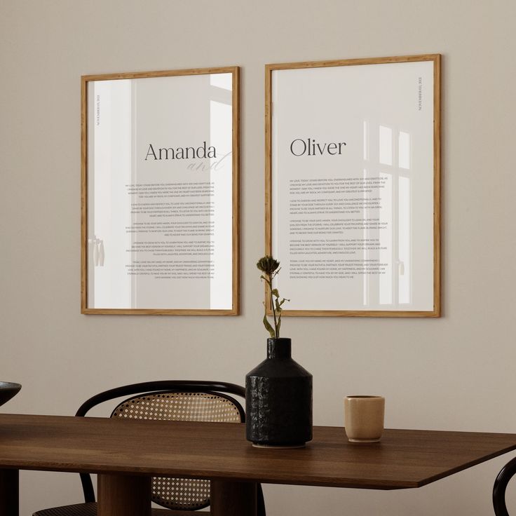 two framed posters on the wall above a dining room table with chairs and vases