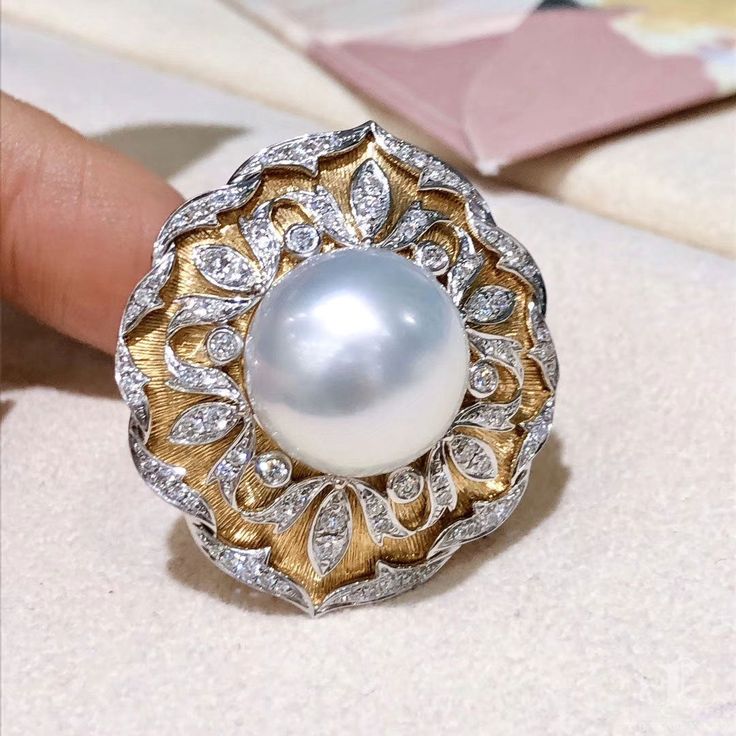 This royal style ring using Italy Buccellati process. Product Information OriginSouth Sea Pearl Jewelry Processed in Japan MaterialSouth Sea Pearl, 18k Gold and Natural Diamond DimensionsTop Approx. 3.0 x 2.7 cm Pearl Shaped: Round Size: 14 mm Quality: AAAA Nacre: Very Thick Color: White Luster: Very High Accessories Metal: 10.5g of 18k Gold and White Gold Other: 0.85ct of Natural Diamond Luxury Diamond White Dome Ring, Luxury White Diamond Dome Ring, Luxury White Dome Ring With Brilliant Cut, Luxury White Gold Dome Ring With Gemstone, Luxury Dome Ring With 17 Jewels, Luxury Dome Ring With Pave Setting As Gift, Luxury Dome Ring With Pave Setting For Gift, Luxury Pearl Ring With Diamond Pave Setting, Luxury Dome Ring For Wedding