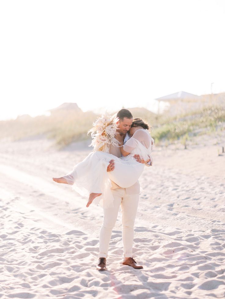 a bride carrying her groom on the beach