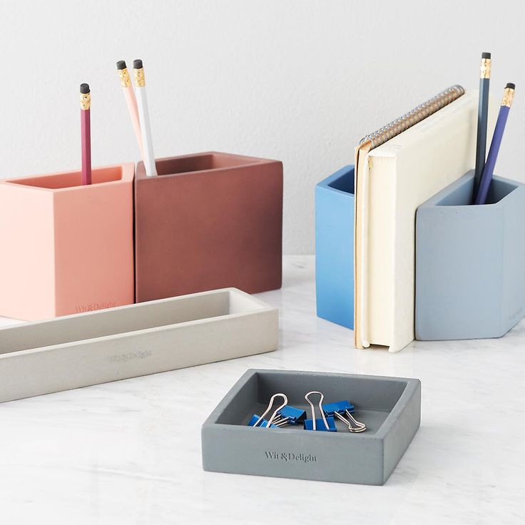 three office supplies sitting on top of a white counter next to a book and pen holder