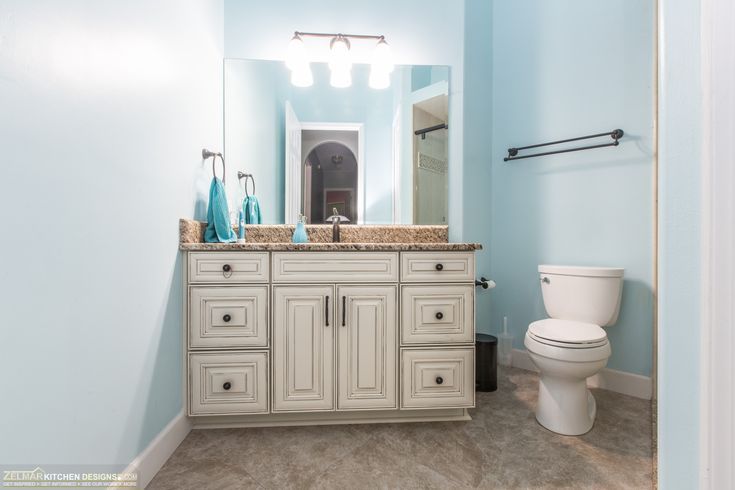 a white toilet sitting next to a bathroom sink in a blue walled room on top of a hard wood floor