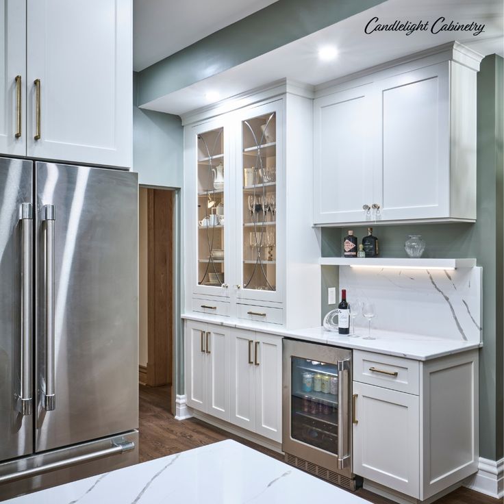 a kitchen with white cabinets, stainless steel appliances and marble counter tops is seen in this image