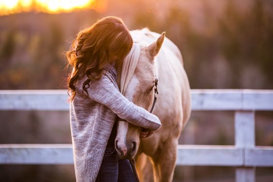 a woman standing next to a white horse