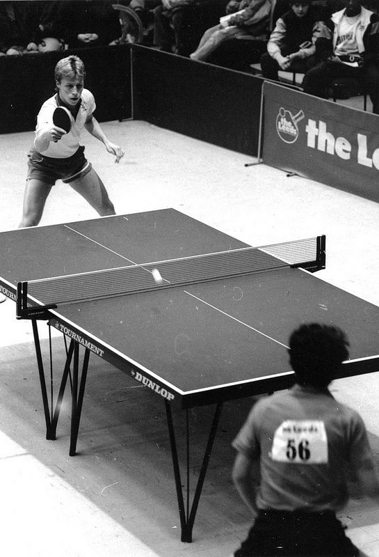 two people playing ping pong in front of an audience