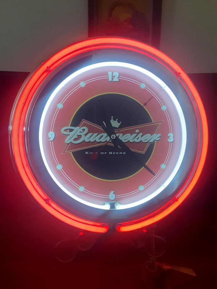 a neon clock with the budweiser logo on it