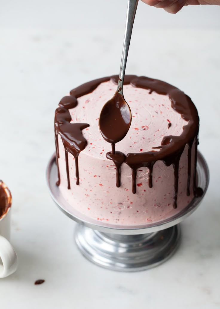 someone is spooning chocolate onto a pink cake