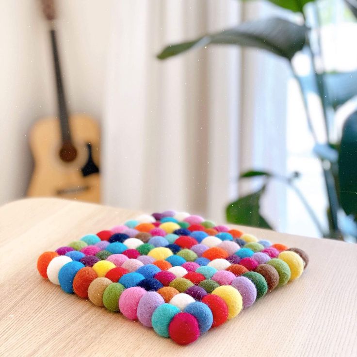 a wooden table topped with lots of colorful pom poms