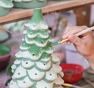 a person is painting a ceramic christmas tree