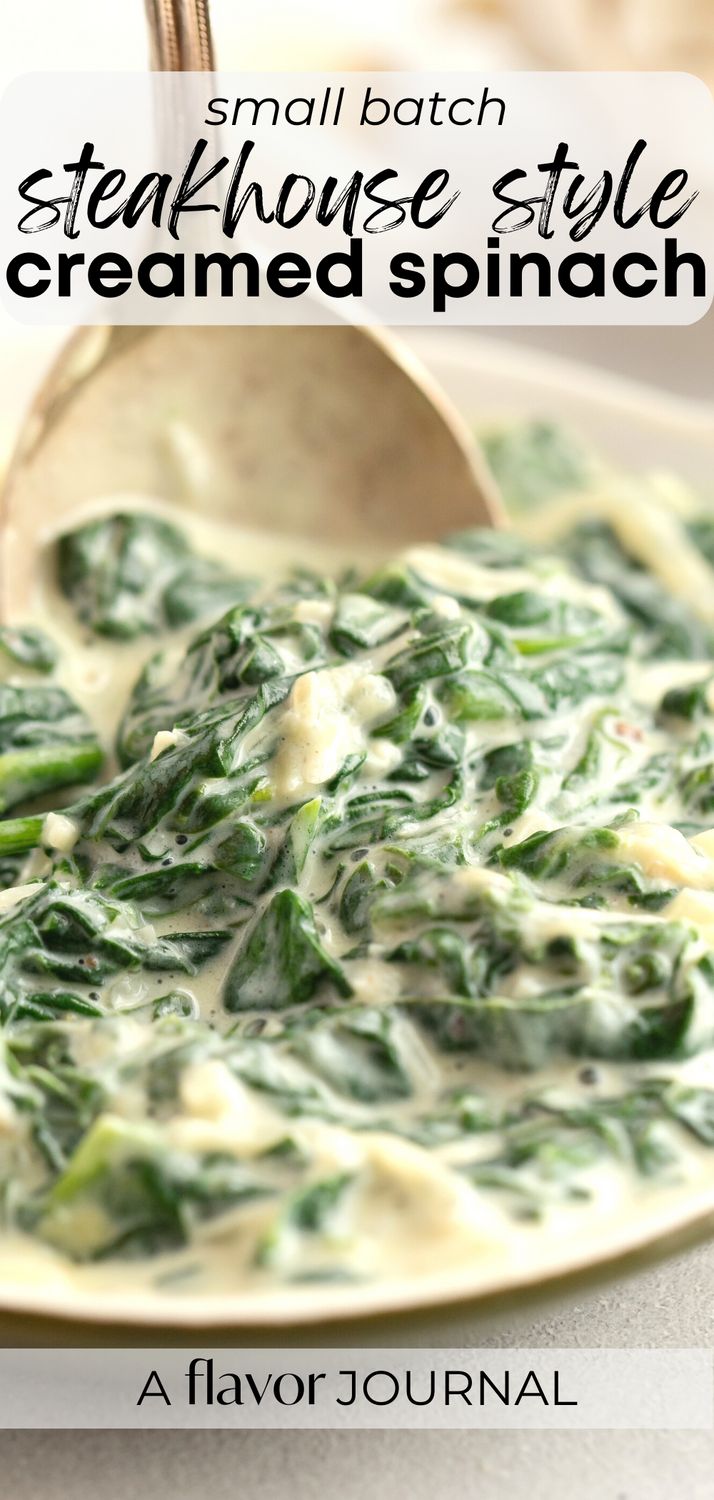 a white plate topped with spinach covered in cheese and sauce next to a spoon