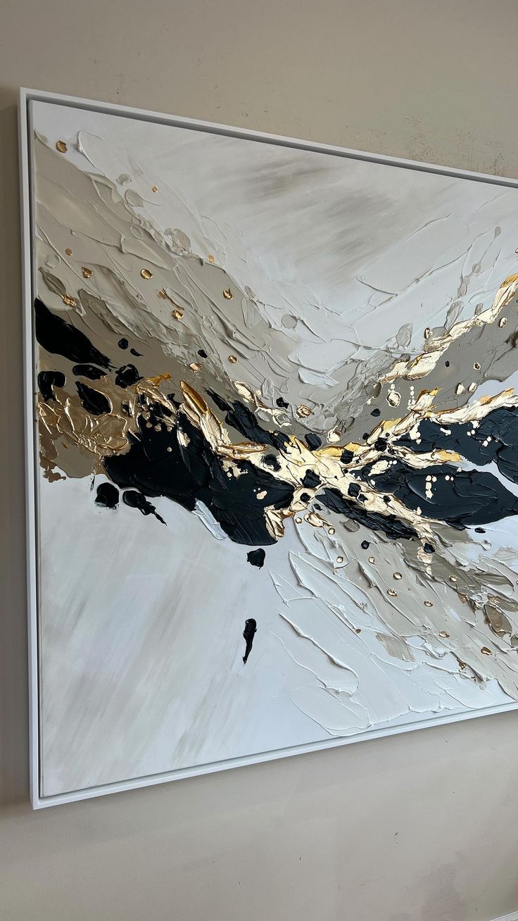 an abstract painting hanging on the wall in a room with white and gold paint strokes