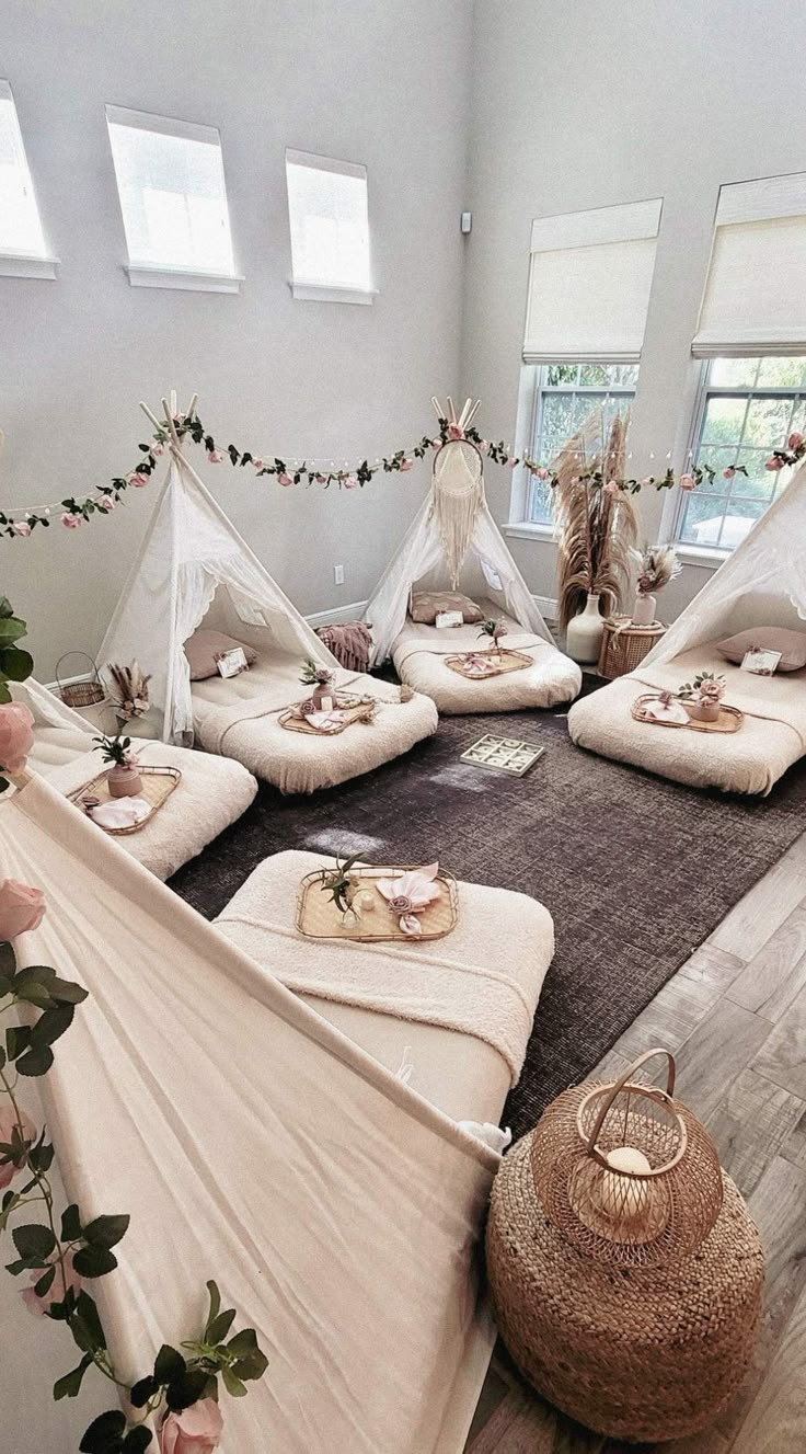 a room filled with lots of white beds covered in blankets and pillows on top of a wooden floor