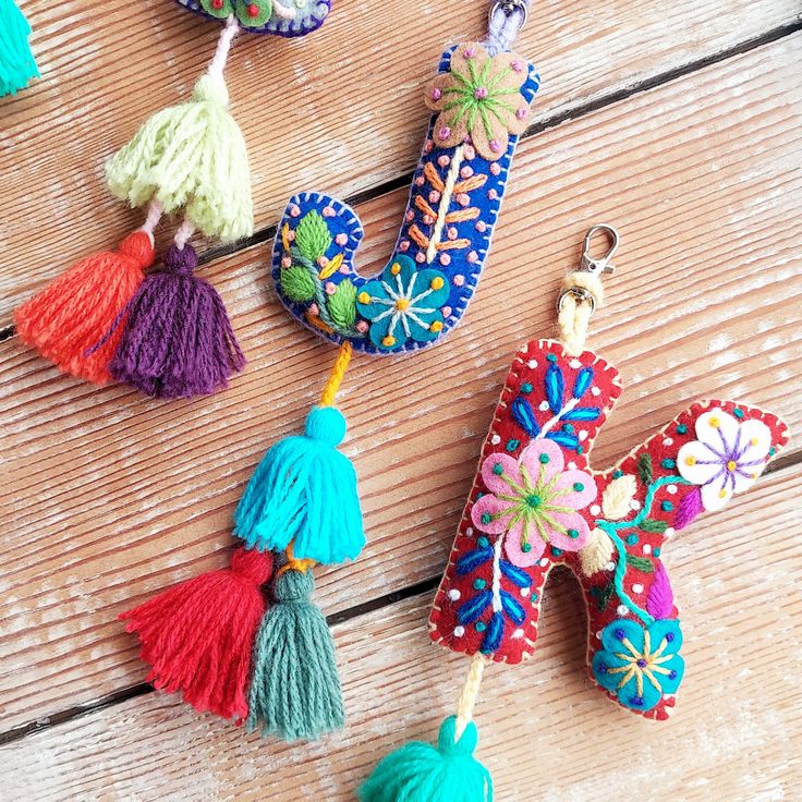 colorful keychains with tassels hanging from them on a wooden surface,