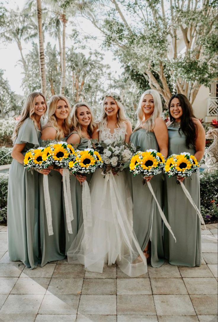 a group of women standing next to each other holding bouquets of sunflowers