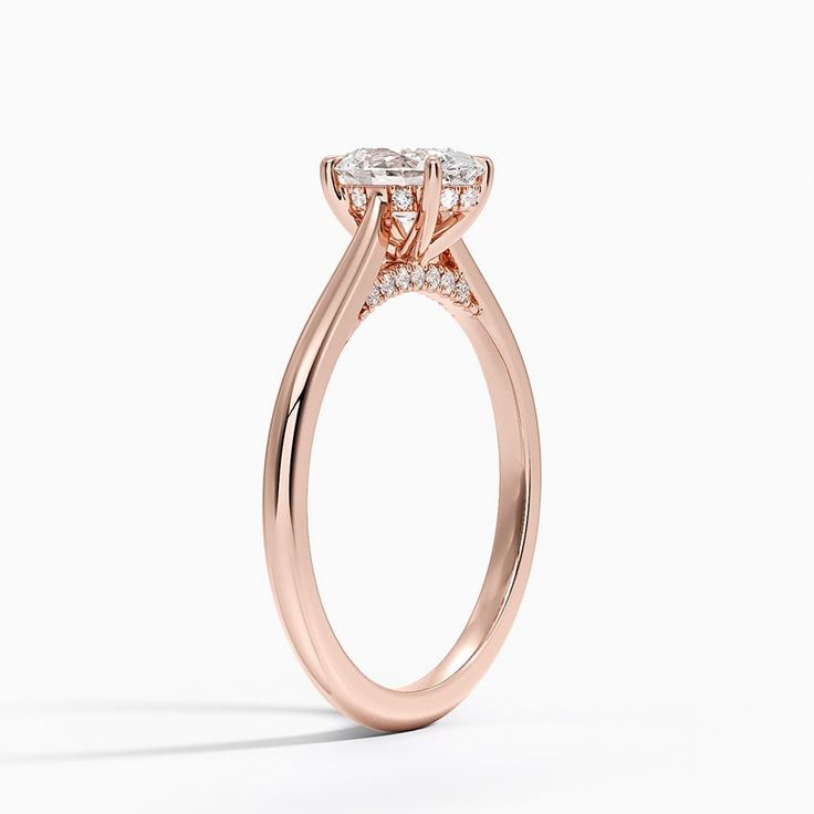 a rose gold engagement ring with three stones on the band and an oval shaped center stone