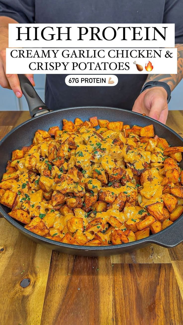 a pan filled with chicken and potatoes on top of a wooden table