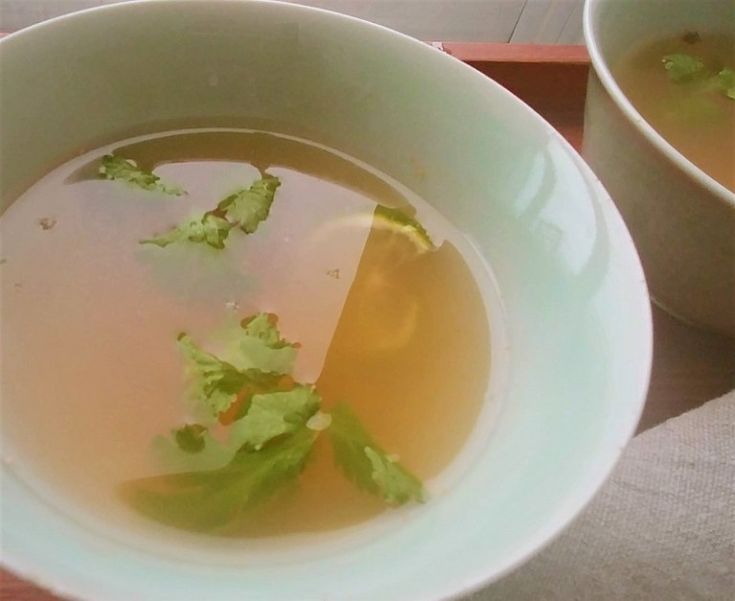 a bowl of soup with lettuce in it and another bowl next to it