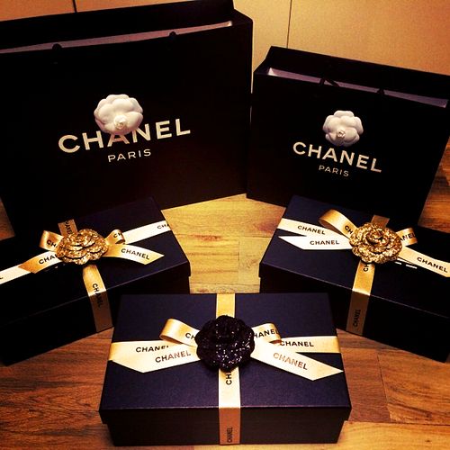 three black boxes with gold ribbons and bows on them are sitting on a table next to each other