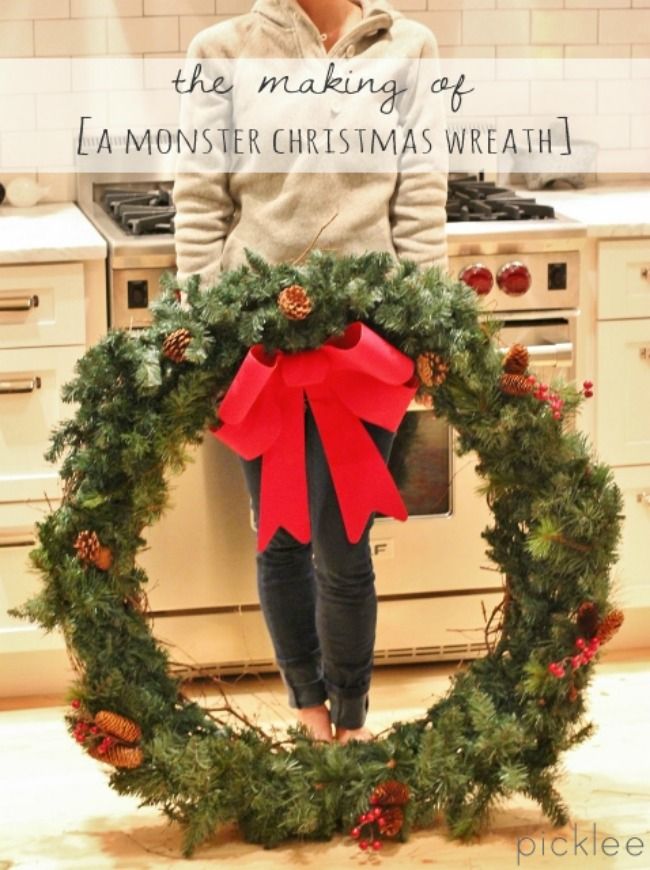 a woman standing in front of a christmas wreath