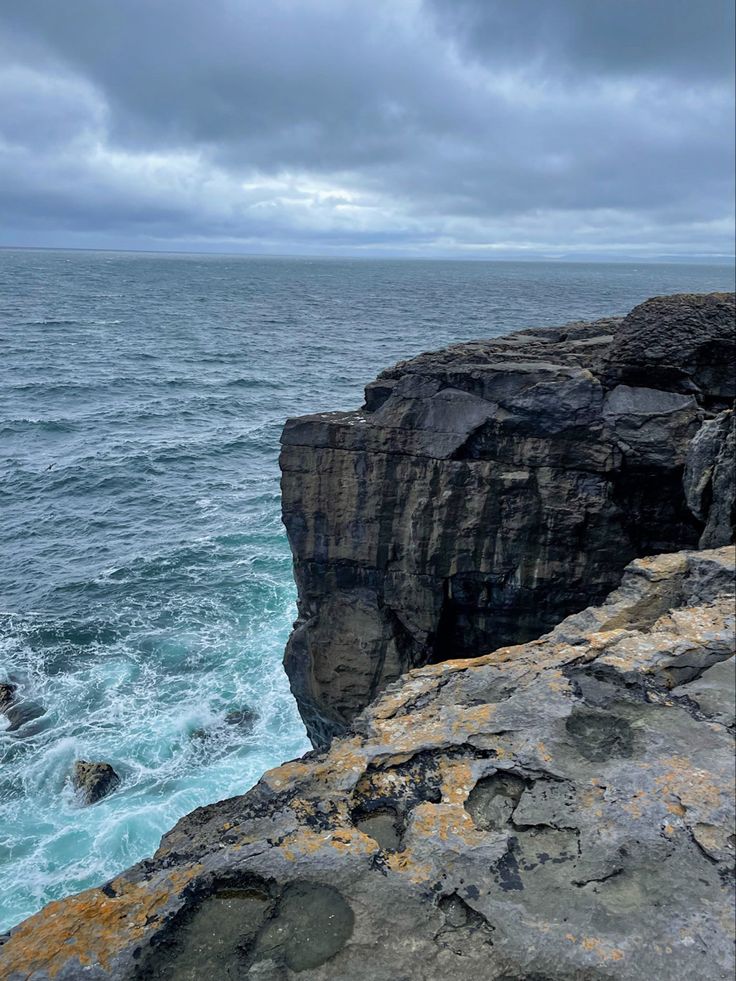 a person sitting on top of a cliff near the ocean