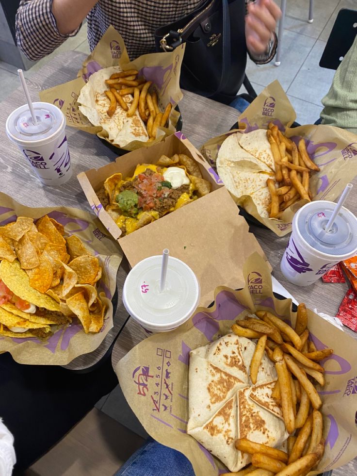 some people are sitting at a table with many different foods and drinks on the table