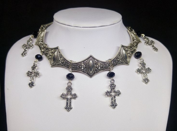 Victorian Gothic metal choker with hollow crosses and black crystal beads, ornate metal necklace, Victorian jewelry, Gothic jewelry A beautifully ornate gothic silver metal choker with Victorian hollow cross charms and black faceted crystal beads. It measures approx. 11 inches in length and has lobster clasp fastening and an extension chain, so that it can be adjusted to fit the neck. The choker is made up of 7 silver toned metal ancient style sections that have intricate detailing. A marvelous Gothic Cross Pendant Jewelry For Halloween, Gothic Silver Necklaces For Festival, Gothic Metal Choker For Festivals, Gothic Gold Cross Pendant Jewelry, Gothic Metal Necklace, Gothic Silver Festival Jewelry, Gothic Silver Jewelry For Festival, Gothic Festival Choker Jewelry, Gothic Metal Cross Pendant Jewelry