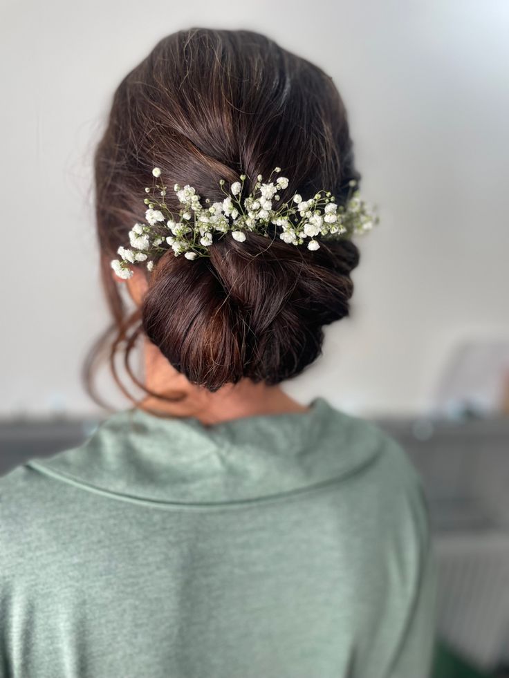 a woman wearing a hair comb with white flowers in it's bun hairstyle