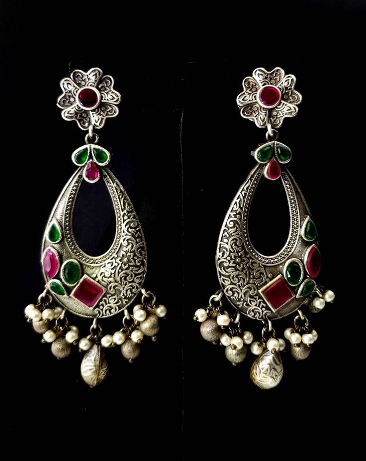 Stunning German silver Indian Chandbali earrings, embellished with sparkly cut CZ stones. Eye catching asymmetric design with a scrolling floral pattern on one half of the earring, and the CZ stones on the other half! Beautiful dangly pearls and silver color stamped balls move when you move, in a very alluring way! Pretty ear stud in shape of flower. Grey finish, polished to a lovely soft lustre. Lots of intricate detail! Excellent quality and craftsmanship! Length 3 3/4 in Width 2 in Weight 14 Silver Pearl Earrings With Stone Work For Gift, Silver Pearl Earrings With Stone Work For Celebration, Silver Fusion Bridal Earrings With Intricate Design, Silver Cutdana Jhumkas For Celebration, Fusion Style Silver Chandbalis For Festive Season, Silver Meenakari Danglers, Silver Hand Set Temple Jewelry Danglers, Silver Temple Jewelry Chandbalis For Wedding, Silver Fusion Style Chandbalis For Festive Occasions