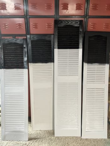 three white and black shutters in front of a red wall