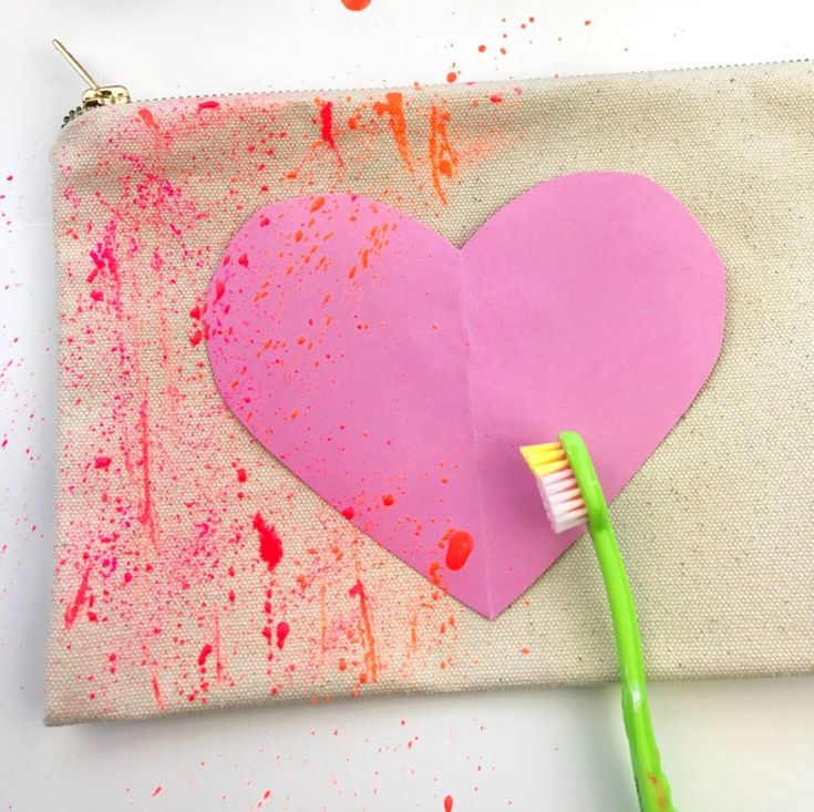 a pink heart shaped paper with a toothbrush in it on top of a white surface