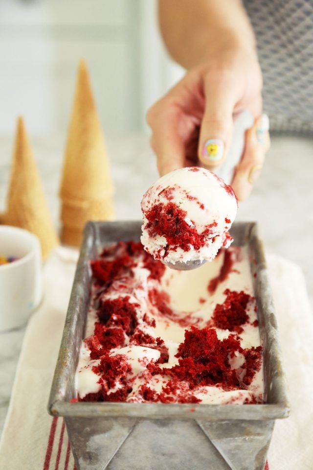 a person scooping ice cream out of a pan with red and white toppings