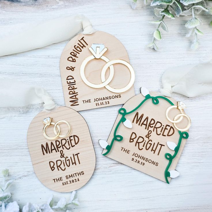 three wooden key chains with wedding rings on them and the words married and brought in green