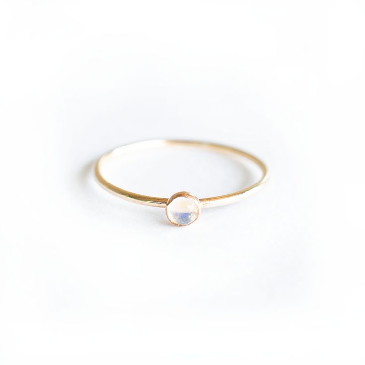 Introducing our Gold Tiny Moonstone Ring featuring a stunning 3mm hand picked Moonstone. Each stone is unique and since these are natural Moonstones , no two stones will ever be the alike. This ring is handmade with a 14k Gold filled ring and a stunning natural Moonstone set in a gold filled bezel. Available in size 4 - 11 Minimalist Moon Shaped Promise Ring, Promise Crystal Ring With Moon Phase, Gift Stackable Rings With Moon Phase Design, Round Moon Phase Crystal Ring, Moon Phase Crystal Promise Ring, Stackable Moonstone Promise Ring Jewelry, White Stackable Moonstone Rings With Ethical Gemstones, Moonstone Birthstone Ring For Promise, Delicate Moonstone Ring With Round Band As Gift