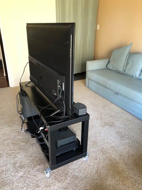 a flat screen tv sitting on top of a black stand in front of a couch