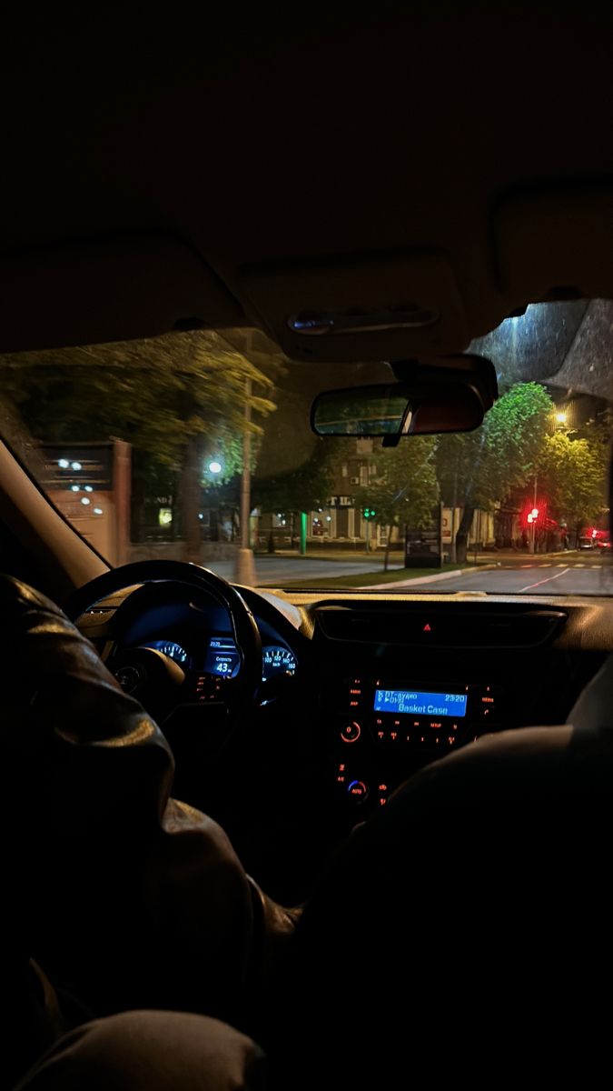 the interior of a car at night with its lights on and dashboard illuminated by streetlights