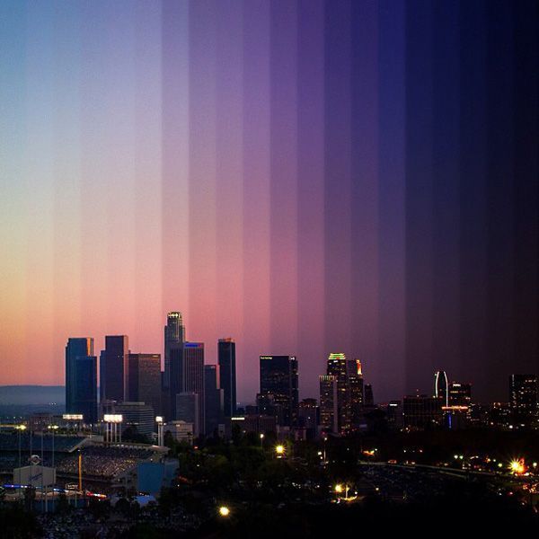 the city skyline is lit up at night with many vertical lines in the foreground