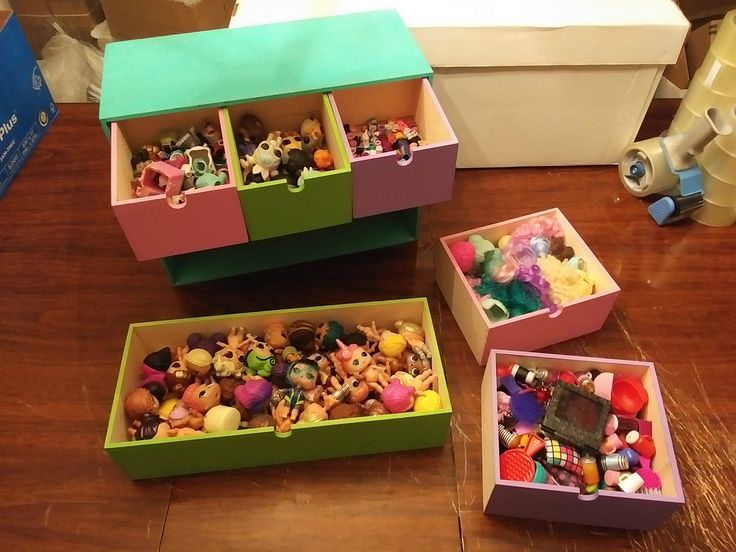 three boxes filled with toys on top of a wooden floor next to a box full of small toy figurines