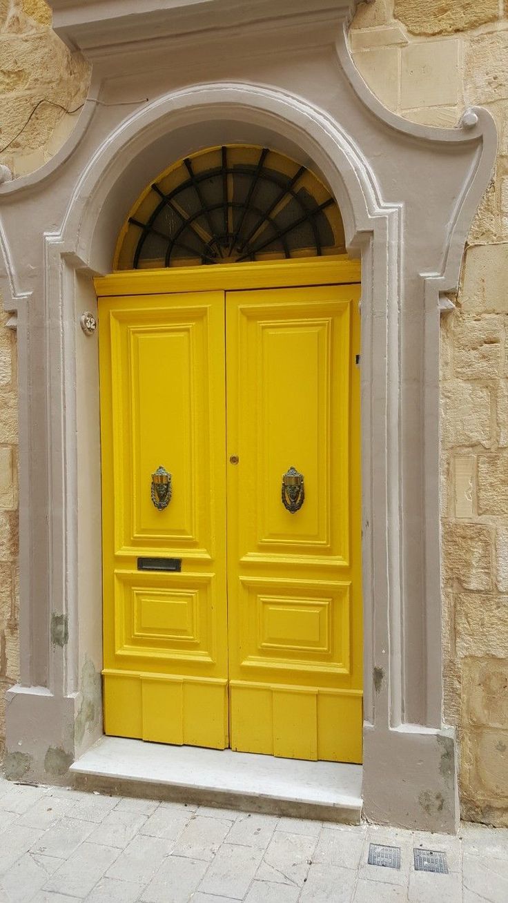 two yellow doors are open in front of a stone building