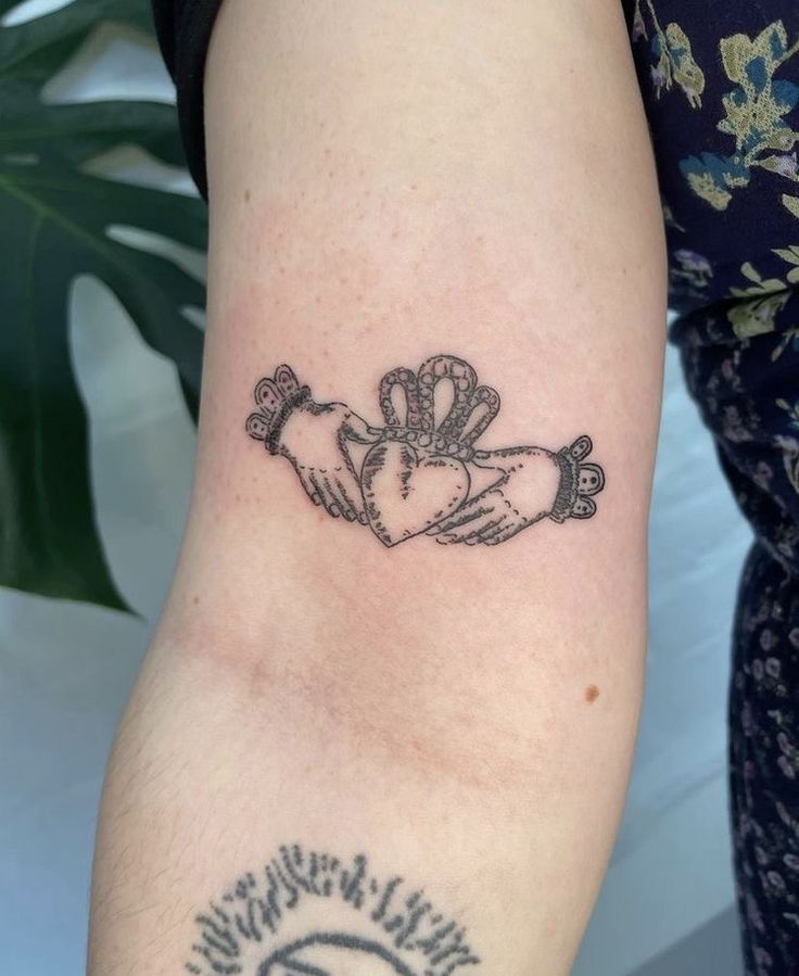 a woman's arm with a tattoo on it that has two hands holding hearts