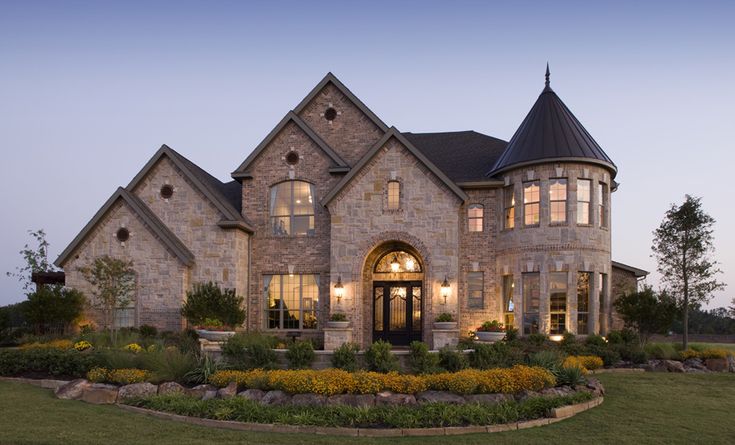 a large house with lots of windows and landscaping around the front yard at night time