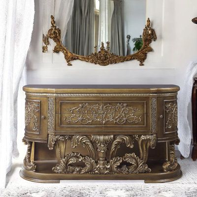 an ornately decorated chest in front of a mirror and table with a vase on it