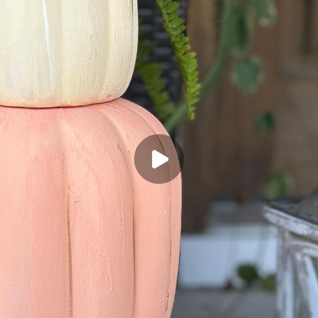 a pink vase sitting on top of a table next to a potted green plant