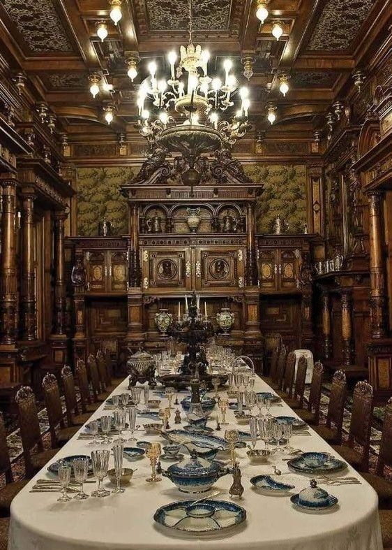 a long table with plates and silverware on it in front of a chandelier