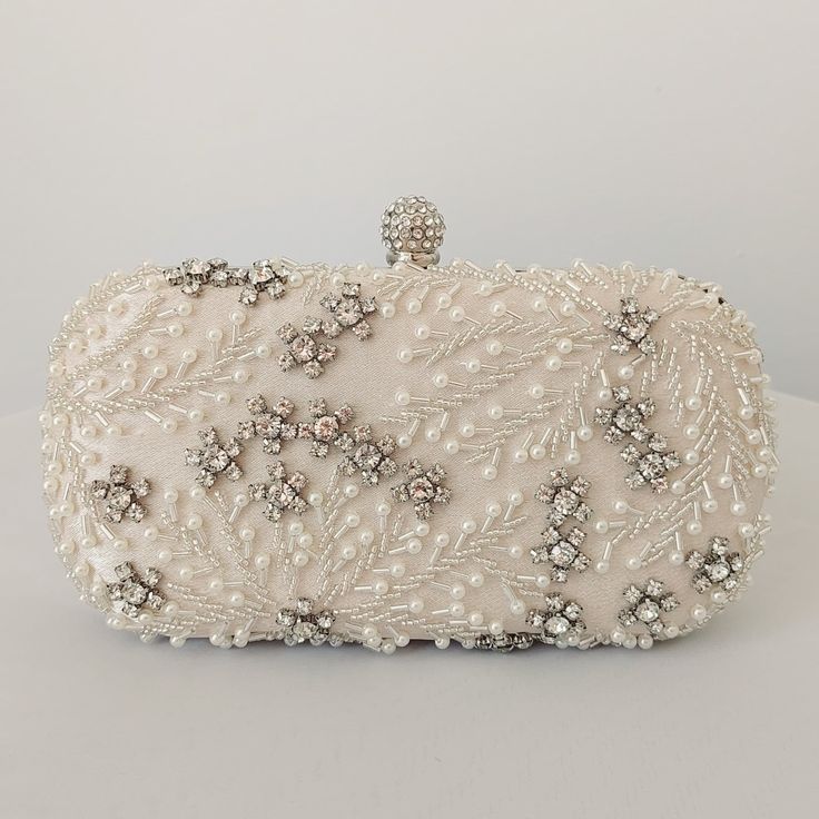 This stunning bridal clutch never fails to turn heads with its understated elegance and classic design. Adorned with white pearls and set off with sparkling CZ stones, this bridal clutch is the very picture of refinement. The crystal clasp and intricately encrusted front give this bridal clutch the look and feel of opulence and at the back of the clutch has the feel of smooth, soft satin. Available with a detachable long, metal shoulder chain, you can either drape your bridal clutch over your sh White Couture, Bridal Clutch Purse, Silver Clutch Purse, Bridal Clutch Bag, Pearl Clutch, Bridal Bag, Silver Clutch, White Clutch, Crystal Bags