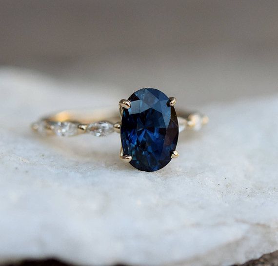 a blue stone ring sitting on top of a white piece of paper next to a rock