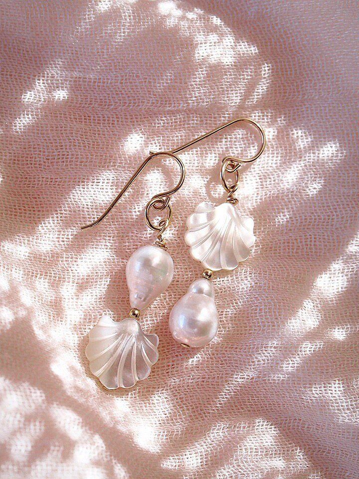 These asymmetrical carved Seashell and Baroque Pearl Earrings make beautiful simple statements. Seemingly plucked straight from the ocean, the luminous, organic white pearls sway and illuminate in the light. Wear these unique pearl, shell, and gold earrings for a modern upgrade.✦ DETAILS ✦✧ Name: Momi - (MOH mee) - pearl.✧ 14kt Gold Filled.✧ Genuine Freshwater Baroque Pearls.✧ Carved Mother of Pearl Seashells.✧ All Ke Aloha Jewelry pieces come packaged thoughtfully, beautifully, and ready for gi Seashell Earrings Aesthetic, Shell Pearl Earrings, Mermaid Core Earrings, Delicate Baroque Pearl White Earrings, Seashell Jewelry Aesthetic, Pearl Drop Shell As A Gift, White Shell-shaped Jewelry With Pearl Pendant, White Baroque Pearl Earrings As A Gift, Elegant Pierced Jewelry In Mother Of Pearl