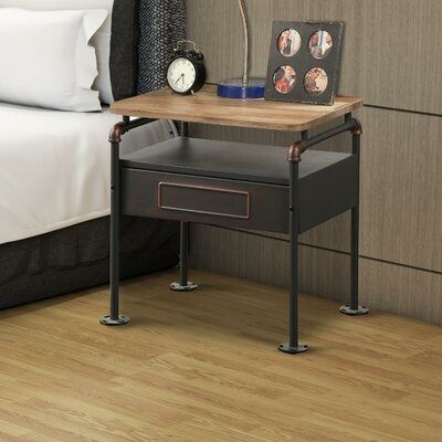 a nightstand with a clock on it next to a bed