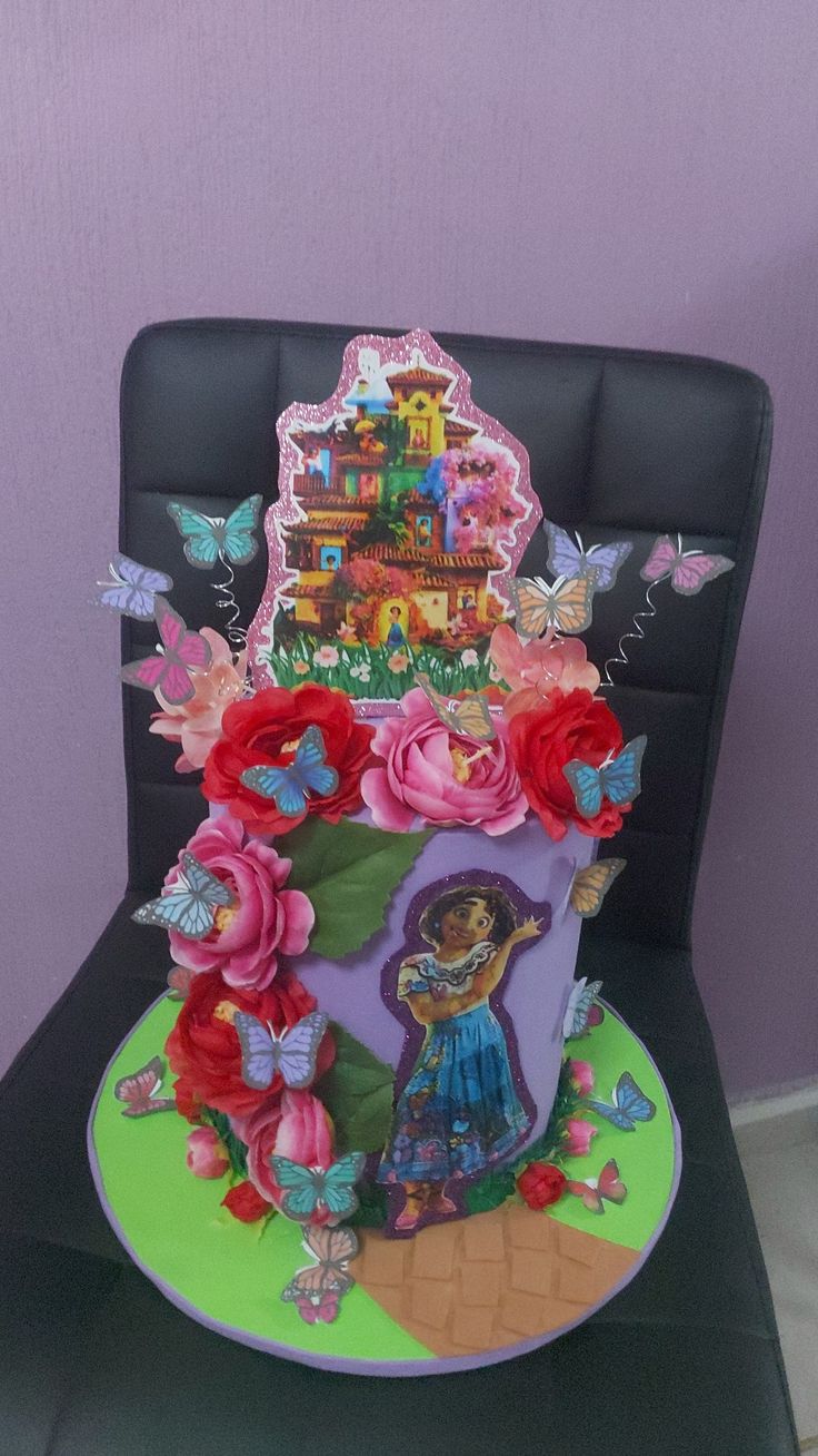 a birthday cake decorated with flowers and butterflies on a chair in front of a purple wall