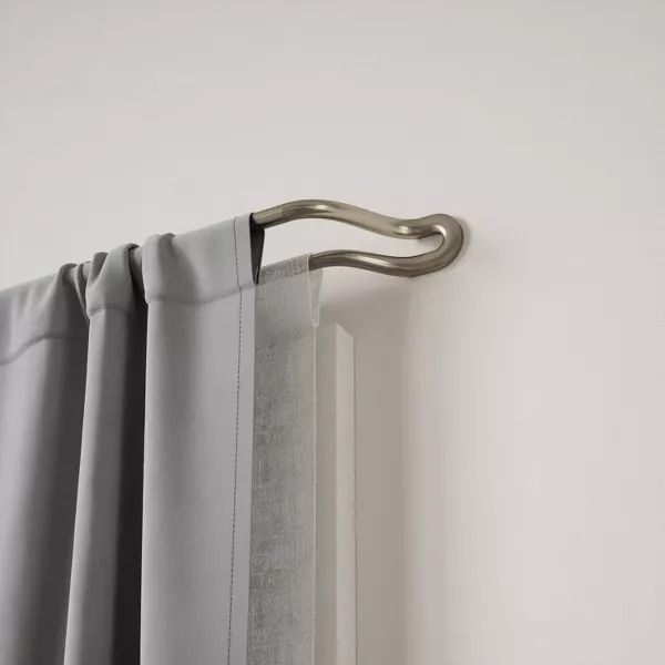 an open curtain with a metal handle hanging from it's side, in front of a white wall